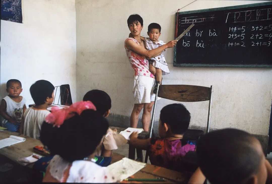 1998年，在山西省太原市的一个小学教室里，一名女教师抱着孩子教学。斎藤康一作品.jpeg