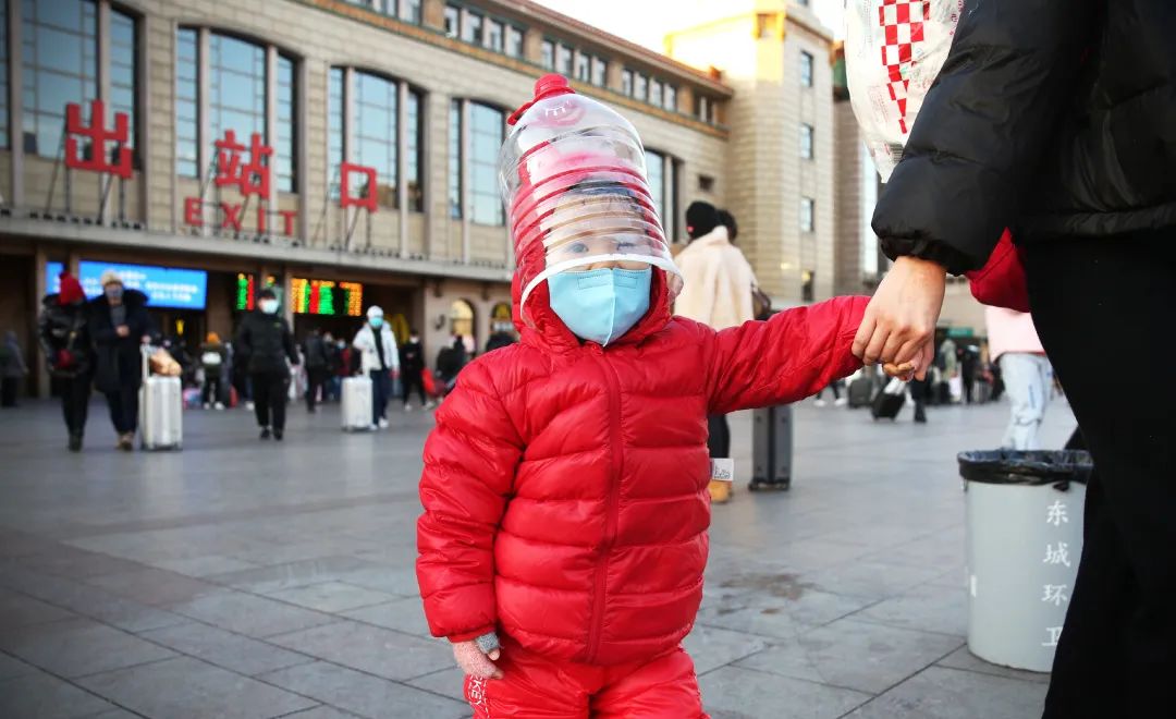 2020年，新冠肺炎疫情暴发初期，小孩儿头戴大塑料瓶，被母亲牵着手走出北京站。片岡航希作品.jpeg